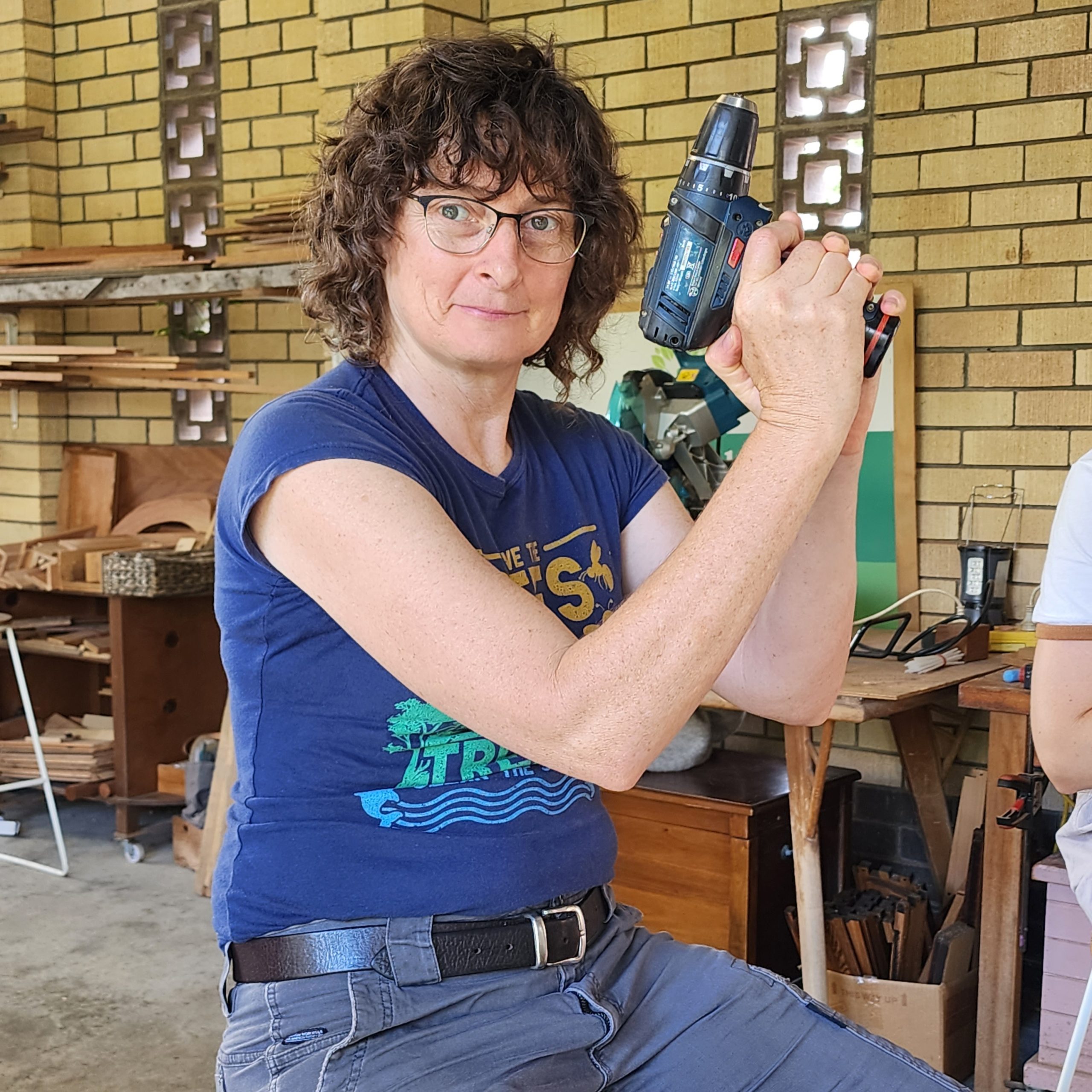 A woman playfully posing with a cordless drill during a Woodwork for Women class.